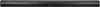 A close-up, horizontal shot of a dark, cylindrical object, likely a soundbar, with subtle reflections indicating a metallic or glossy surface. The background is a gradient of light gray to dark gray. Produktbild-Vorschau