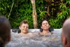 A family relaxing in a hot tub outdoors surrounded by lush greenery. Náhled obrázku produktu
