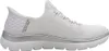 A side view of a white Skechers slip-on shoe with silver accents. Voir les images du produit