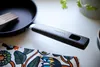 A close-up shot of a frying pan handle with the brand name visible, resting on a patterned cloth. Podgląd zdjęcia produktu