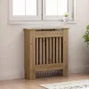 A wooden radiator cover is placed in front of a window with a small plant on the windowsill. Náhľad obrázku produktu