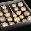 A box of champagne-colored Christmas ornaments with gold accents. Produktbild-Vorschau