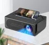 A black mini projector is placed on a light gray surface, with a smartphone displaying a movie on top of it. Blue light emanates from the projector lens. Náhľad obrázku produktu