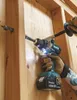 A person wearing work gloves is using a Makita drill to drill a hole in a wooden wall. Anteprima dell’immagine prodotto