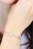 A close-up shot of a woman's wrist wearing a silver bracelet with a circular, sparkling pendant. Podgląd zdjęcia produktu