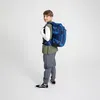A young boy wearing a backpack and looking over his shoulder. Produktbild-Vorschau