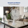A white desk fan is placed on a glass-top desk next to a laptop in a home office setting. Produktbild-Vorschau