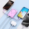 A pink power bank is charging multiple devices, including two smartphones and a pair of wireless earbuds. Náhled obrázku produktu