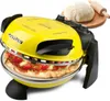 A yellow pizza maker with a pizza inside, and a ball of dough and rolling pin in the background. Podgląd zdjęcia produktu