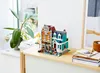A LEGO Creator Expert building set is displayed on a wooden cabinet next to a plant and books. Produktbild-Vorschau