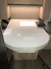 A bed with a white fitted sheet in what appears to be a camper van or RV. Produktbild-Vorschau