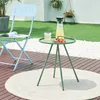 An outdoor scene with a light blue chair, a green side table with drinks and fruit, and a round rug on a wooden deck. Náhled obrázku produktu