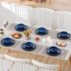A dining table set for a meal with blue tableware, croissants, strawberries, and cupcakes. Voir les images du produit