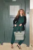 A woman stands in front of a green door, holding a tote bag. Náhľad obrázku produktu
