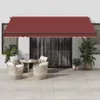An outdoor patio scene with a red awning extended over a glass sliding door, featuring a small round table and two wicker chairs with cushions. Produktbild-Vorschau