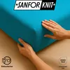 Hands are shown adjusting a turquoise fitted sheet on a wooden surface, with brand and certification logos visible. Produktbild-Vorschau