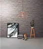 A modern living room scene with a stone-effect wallpaper, a geometric pendant light, a framed artwork, decorative pillows, and a cactus on a stool. Náhled obrázku produktu