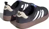 A pair of black Adidas Puffylette sneakers with white stripes and beige accents are shown from a side-angle. Podgląd zdjęcia produktu