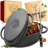 A cast iron pot filled with stew, with its lid partially open, and accompanying recipe booklets and a meat fork. Produktbild-Vorschau