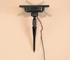 A black solar panel stake with a wire attached, shown against a light peach background. Produktbild-Vorschau