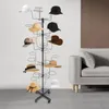 A black metal hat stand displaying various hats in a room with a sofa and a wall. Produktbild-Vorschau