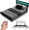A modern black bed with a headboard featuring integrated green LED lighting, shown with bedding and a throw blanket. A remote control for the lights is also visible. Náhľad obrázku produktu