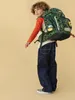 A young boy wearing a backpack and standing against a plain background. Produktbild-Vorschau