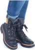 A close-up shot of a pair of black lace-up boots with fur trim, worn with blue jeans. Anteprima dell’immagine prodotto