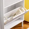 A white shoe cabinet with a tilted open drawer revealing two beige shoes. Náhľad obrázku produktu