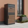 A modern mailbox and parcel box with wood-look elements stands on a paved patio next to a building with a window. Podgląd zdjęcia produktu