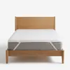 A mattress protector on a bed with a wooden headboard. Produktbild-Vorschau