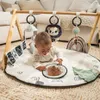 A baby is playing on a playmat under a wooden gymini. Produktbild-Vorschau