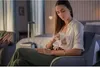A woman is sitting in a chair and using a breast pump. Produktbild-Vorschau