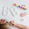 A child's hands are painting a craft set with Paw Patrol characters. Produktbild-Vorschau