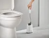 A hand is holding a toilet brush over a toilet bowl. Podgląd zdjęcia produktu