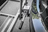 A close-up view of a trailer hitch attachment mechanism next to a car's tire. Podgląd zdjęcia produktu
