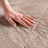 A close-up shot of a hand gently touching a textured carpet. Produktbild-Vorschau
