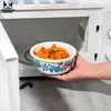 A hand is placing a bowl of pasta into a microwave. Produktbild-Vorschau