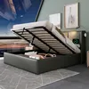 A modern bedroom with a bed that has its storage compartment open, revealing items inside. The bed has a built-in light and charging station. Náhled obrázku produktu