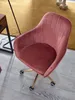 A pink velvet office chair with gold legs and wheels is shown on a wooden floor and a yellow rug. Náhľad obrázku produktu