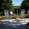 Two gray folding garden chairs are placed on a patio in front of a modern house with a garden. Produktbild-Vorschau