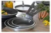 A collection of frying pans with vegetables and carrots in the background. Podgląd zdjęcia produktu