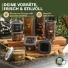 A collection of food storage containers filled with various dry goods like pasta, grains, and spices, arranged on a kitchen counter with some walnuts and wheat stalks. Anteprima dell’immagine prodotto