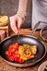 A person is seasoning a meal in a pan. Náhled obrázku produktu