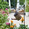 A decorative watering can solar lamp is hanging in a garden among flowers. Anteprima dell’immagine prodotto