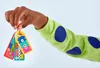 A child's hand holding a set of colorful LEGO DOTS bag charms. Produktbild-Vorschau