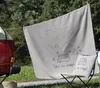 A blanket and pillow with a camping theme are displayed outdoors, with a vintage camper van visible. Produktbild-Vorschau