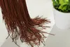 A close-up of brown fringe curtain strands hanging down, with a white potted plant in the background. Produktbild-Vorschau