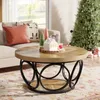 A round coffee table with decorative items and a Christmas tree in the background. Produktbild-Vorschau