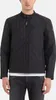 A man wearing a black quilted jacket and grey jeans. Produktbild-Vorschau
